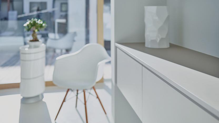 Weißes Regal mit Schublade vor weißem Stuhl